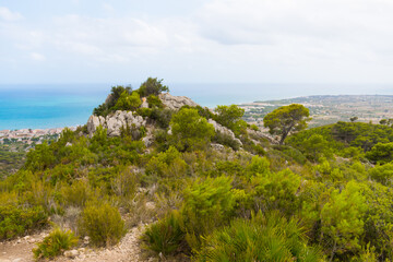 Fototapeta premium Rocky Mountain Overlooking Bright Blue Mediterranean Sea On A Sunny Summer Day. wide shot