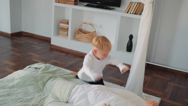 A little son running to his father at the bedroom at home