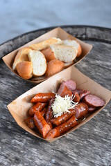 Roasted sausages with horseradich and bread served on a paper tray - wood board