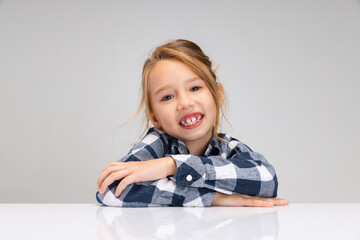 Portrait of beautiful little girl looking at camera, making faces isolated on gray studio background. Human emotions, facial expression concept.