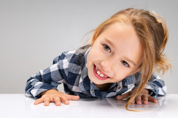 Naklejka premium Close-up cute beautiful little girl looking at camera, making faces isolated on gray studio background. Human emotions, facial expression concept.
