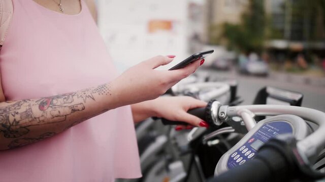Rental bike bicycles using mobile phone app. Close-up of hands with phone.
