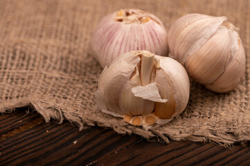 Heads of young garlic on a table covered with burlap, close-up, selective focus.