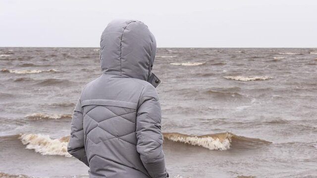A Woman Looks at the Foamy Waves. Windy Autumn Day at the Shore of Lake Ilmen.