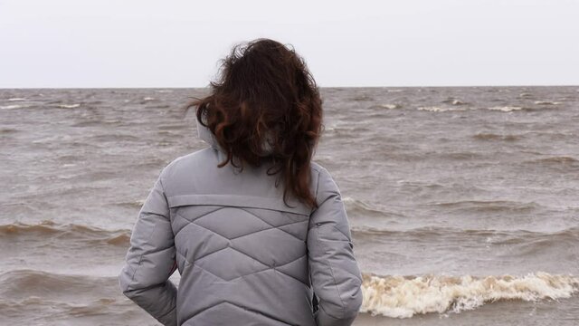 A Woman Looks at the Foamy Waves. Windy Autumn Day at the Shore of Lake Ilmen.