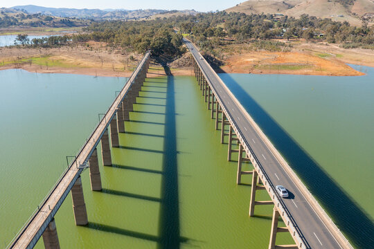 Aerial view of two parallel bridges casting shadows over the water of  large lake