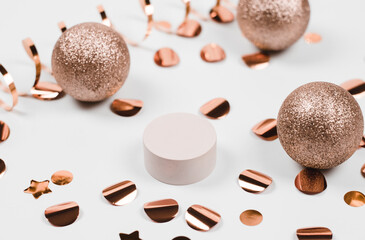Podium with New Year's decor, with red balls, confetti and garland lights. Beige plinth for product...