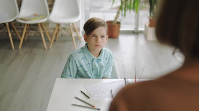 A small boy pupil listening the teacher in the modern art school