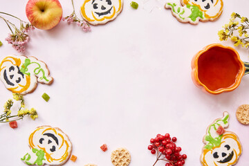 Halloween creative concept background: pumpkin cup and cookies in shape of cute pumpkins. Copy space.Atmospheric aesthetic autumn mood or trick or treat concept. Apples, dry flowers and candied fruit