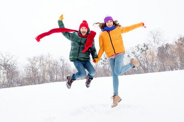 Full length photo of young excited couple happy positive smile have fun jump up enjoy weekend winter park