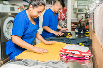 Employees in uniform folding clothes in a laundry service