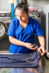 Vertical photo of a woman in uniform folding a piece of cloth in a laundry