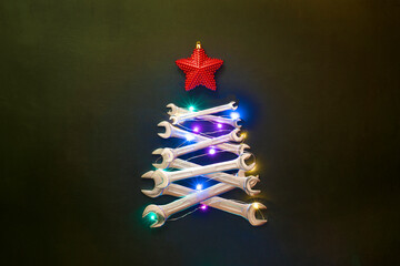 Creative christmas tree on black background, made of wrenches. Industrial greeting card and happy new year concept.
