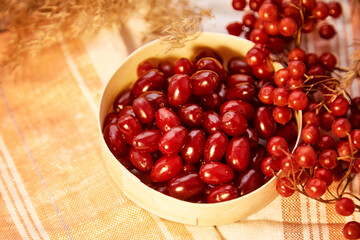 Organic autumn berries of viburnum and dogwood in wooden bowl in cozy home interior. Healthy food for tea, compote and jam concept. Top view background, copy space