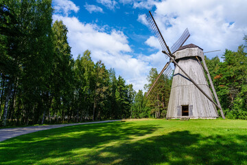 Obraz premium Old wooden windmill over meadow and cloudy sky.