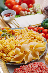 different types of italian pasta on a wooden background with various ingredients for cooking traditional italian dishes