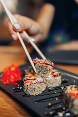 Close up of a sushi plate with a female hand holding chopsticks