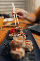 Close up of a sushi plate with a female hand holding chopsticks