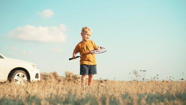 Bottom view of a little boy trying to play badminton in nature