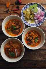 Local northern Thai food Egg noodle curry with pork and beef on wood background