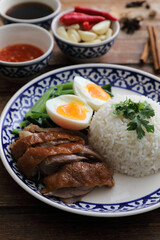 Local Thai food stewed pork leg on rice isolated in wood background