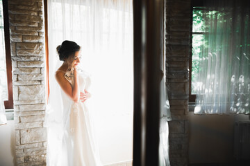 Fototapeta premium Gorgeous bride in robe posing and preparing for the wedding ceremony face in a room