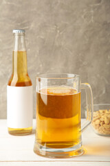 Glass of beer with peanuts on grey background. Vertical photo