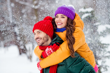 Fototapeta premium Photo of shiny adorable girlfriend boyfriend dressed vests smiling hugging riding back enjoying walking snow outdoors forest