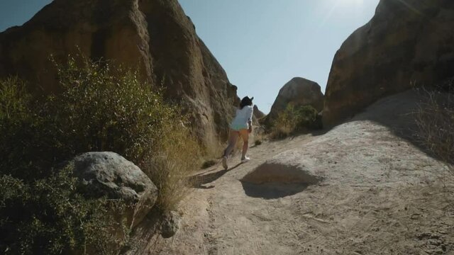Happy raveler girl walking on top of the mountain. Devrent Valley Imaginary Valley full of unique rose rock formations in Cappadocia, Turkey. Travel and vacation concept.