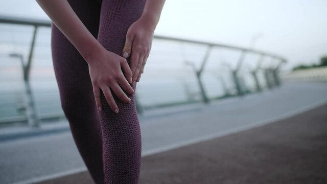 Woman rubbing sore knee, massaging leg, feeling cramps and spasm after jogging