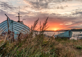 wooden boats moored on a beach meadow at sunset