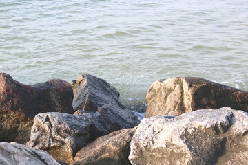 Large stones close-up in sea water in summer on beach against background of sea