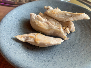 Grilled chicken breast, placed on a plate made of gray ceramic.