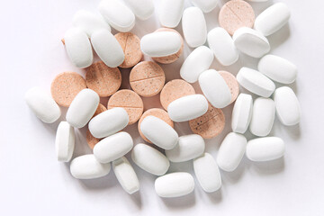 Fototapeta na wymiar White and colored pills on a white background. Oblong and round pills close-up. Healthcare and medicine. 
