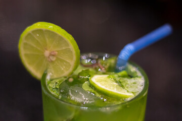 Green cocktail with lime and ice and blue straw