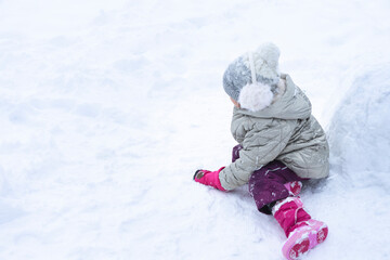 Kid builds a snowman in the winter on a white field of snow. concept of winter games with snow for children, open space
