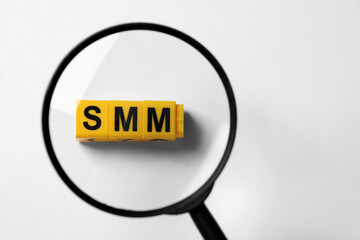 Top view through magnifying glass on yellow cubes with letters SMM, white background
