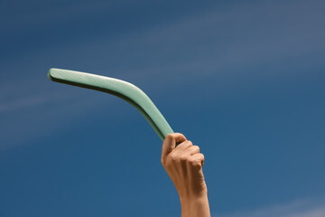 Woman throwing boomerang against blue sky, closeup. Space for text