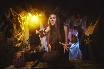 Young girl looking like witch having fun on Halloween in a dark room with yellow light and smoke. Teenager in Carnival and Halloween party