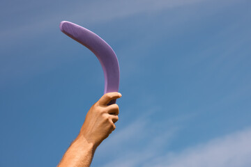 Man throwing boomerang against blue sky, closeup. Space for text