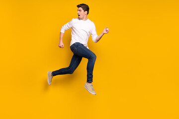 Fototapeta na wymiar Full size profile photo of afraid brunet millennial guy run wear shirt jeans sneakers isolated on yellow background