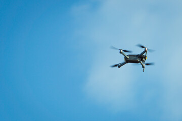 Flying copter against the blue sky. Copter in motion. Small flying drone.