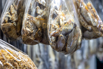 Hanging salted dried sea fishes on a seafood market close up