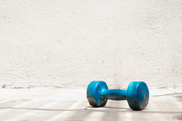 second hand blue dumbbell on the ground (used, rusty) white background, home exercise, space for...