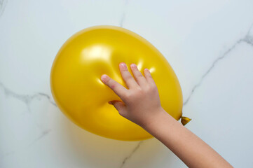 The child's hand is playing a tactile educational game, trying to burst a balloon