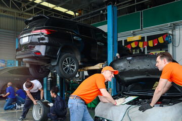Mechanic workers working with engine at garage, car service technician checking and repairing the customer car at automobile service center, vehicle repair service shop concept