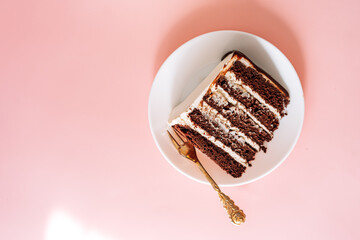 Piece of puff chocolate cake on round plate with small fork