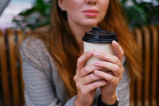 beautiful woman holding coffee in a paper cup. coffee to go. girl drinking tea on the terrace