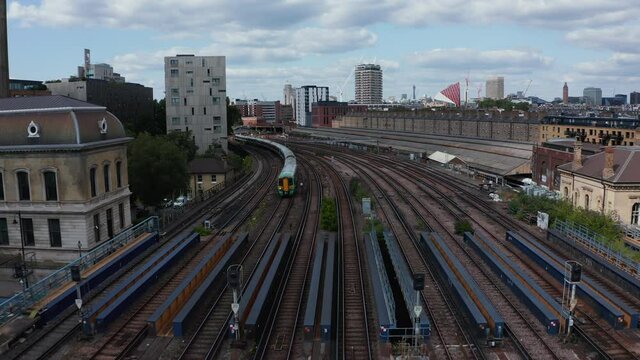 Backwards tracking of passenger train driving on wide multitrack railway bridge over river. London, UK