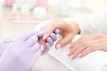 Obraz na płótnie Canvas Manicurist in gloves making manicure for client in salon